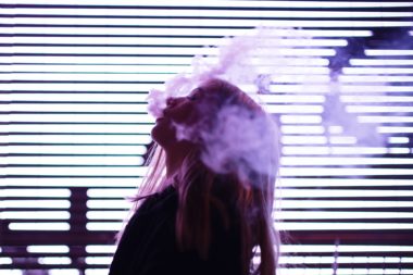 girl smoking against violet lights